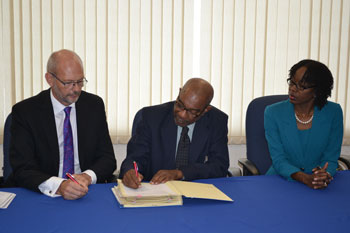 Ambassador Mikael Barfod, Head of the EU Delegation to Barbados and the Eastern Caribbean (L) and Ms Elizabeth Riley, Deputy Executive Director, CDEMA (R) look on as Mr Percival Marie, Director General, CARIFORUM signs the agreement 
