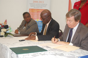 Ms Judy Thomas, Director,  Department of Emergency Management, Barbados,  looks on as  Mr. Jeremy Collymore, Executive Director, CDEMA and Ambassador Acquarone sign the agreement ceremony